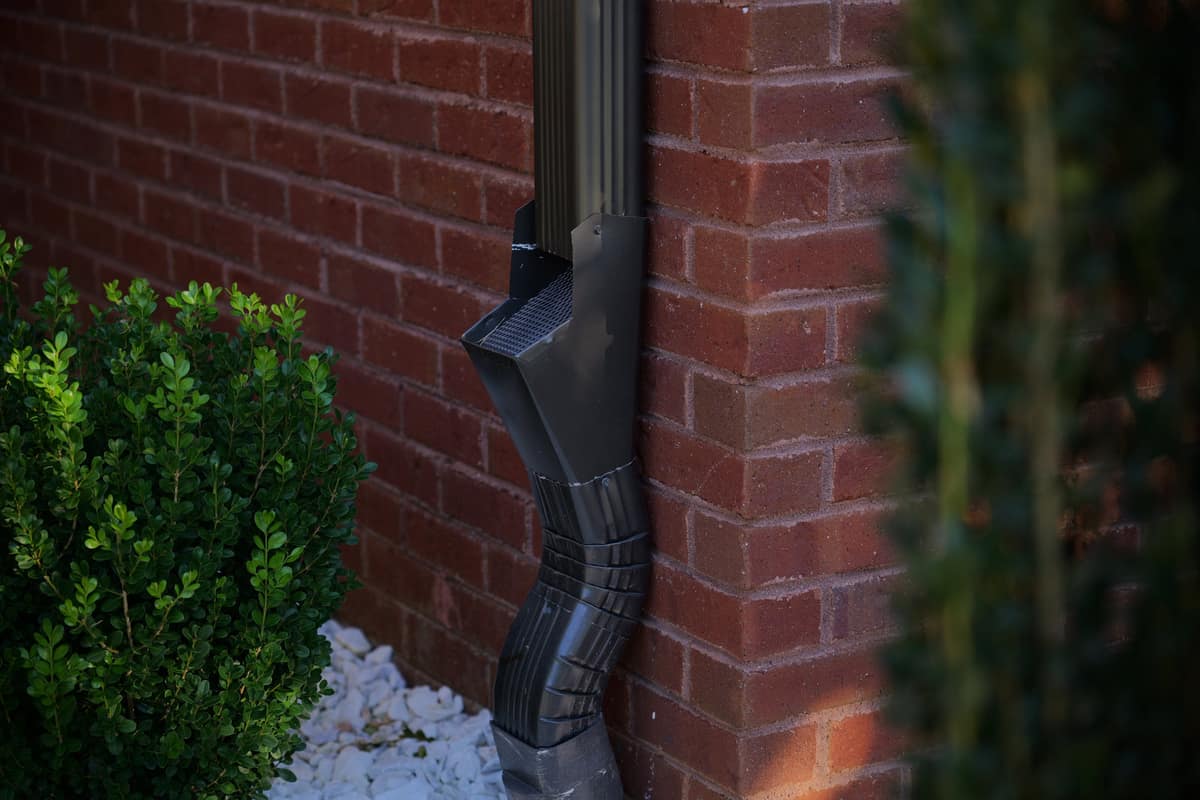 Corrugated 3x4 inch downspout carrying water down an exterior wall