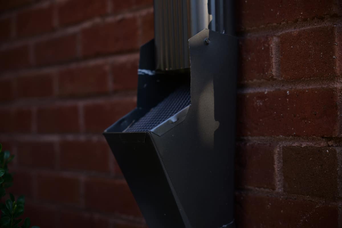 Leaf trap fitted at the base of a downspout to catch debris